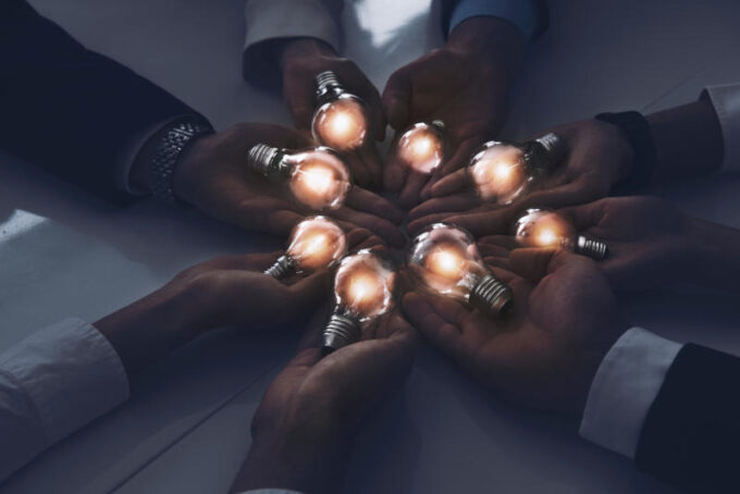 Teamwork and brainstorming concept with businessmen that share an idea with a lamp. Concept company startup